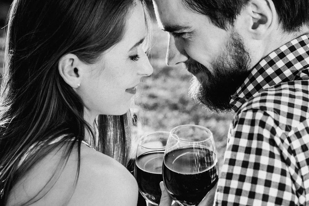 A couple sharing a toast with glasses of red wine