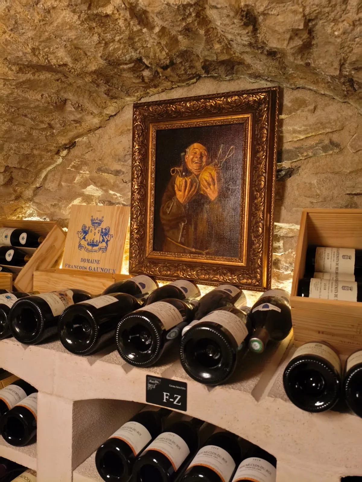 Antique painting of a smiling cellarer above bottles in the wine cellar at Le Cep in Beaune