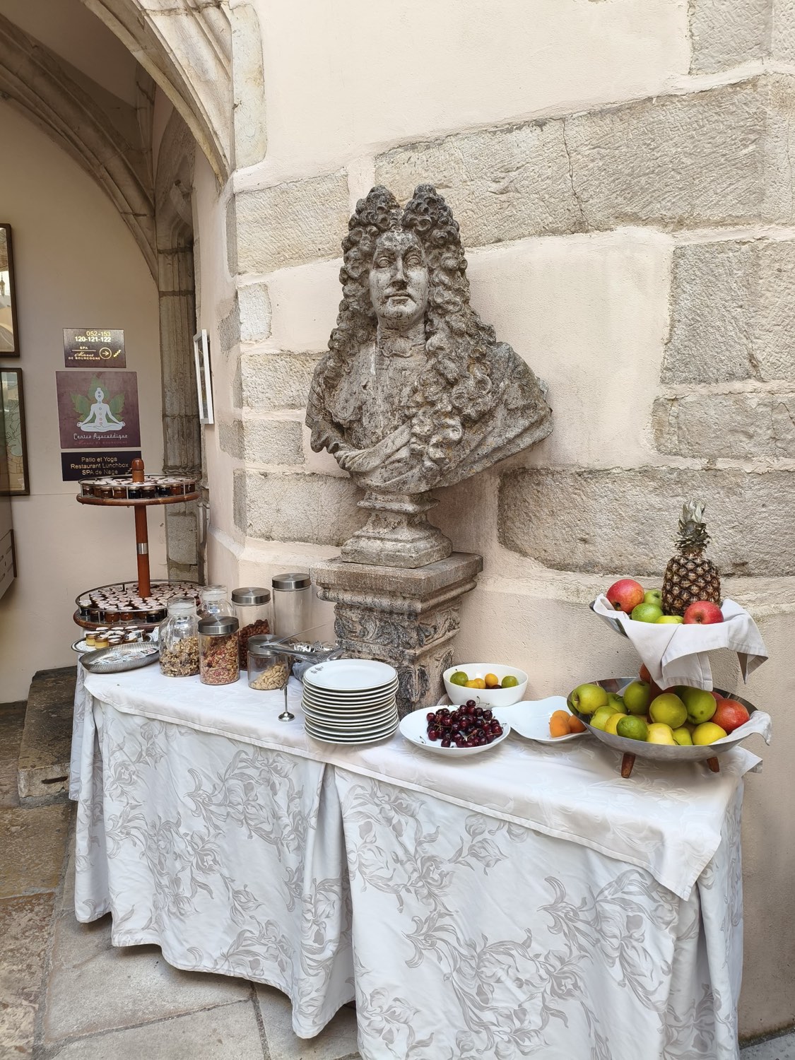 Stone bust of Louis XIV beside the breakfast table in a courtyard at Le Cep in Beaune