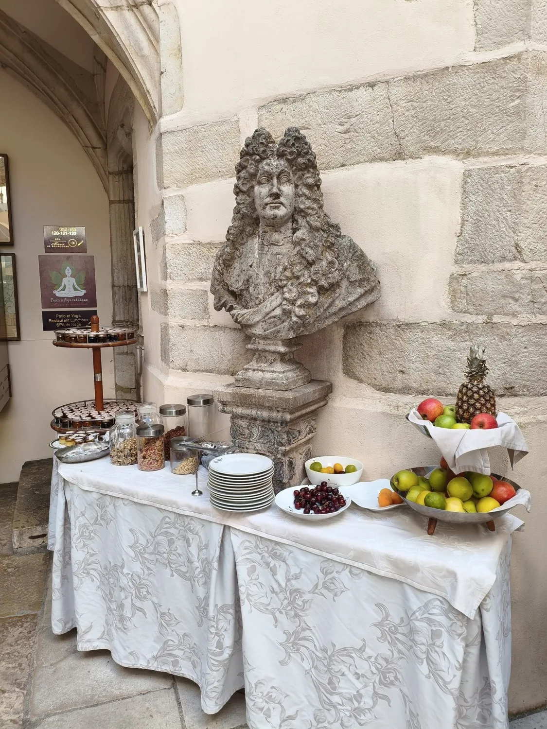 Stone bust of Louis XIV beside the breakfast table in a courtyard at Le Cep in Beaune