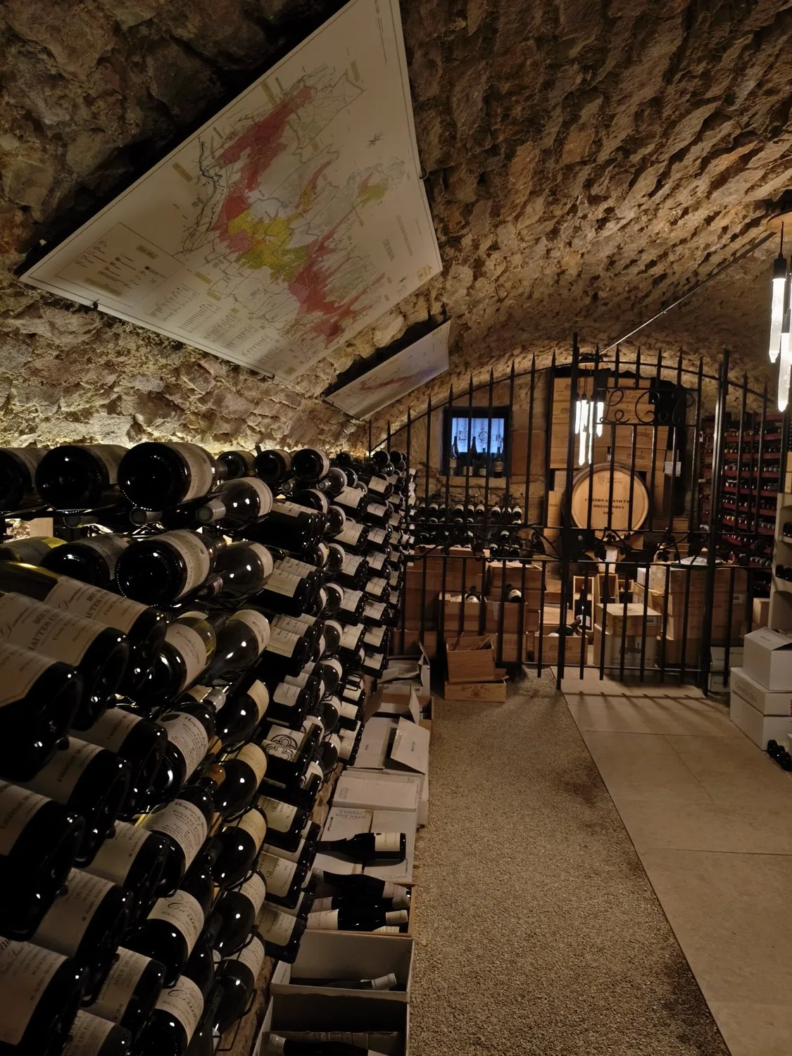 Vaulted stone wine cellar at Le Cep in Beaune with a map of the Burgundy vineyards on the ceiling
