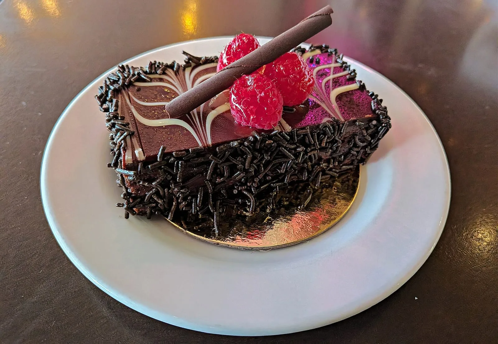A slice of dark chocolate gateau topped with fresh raspberries