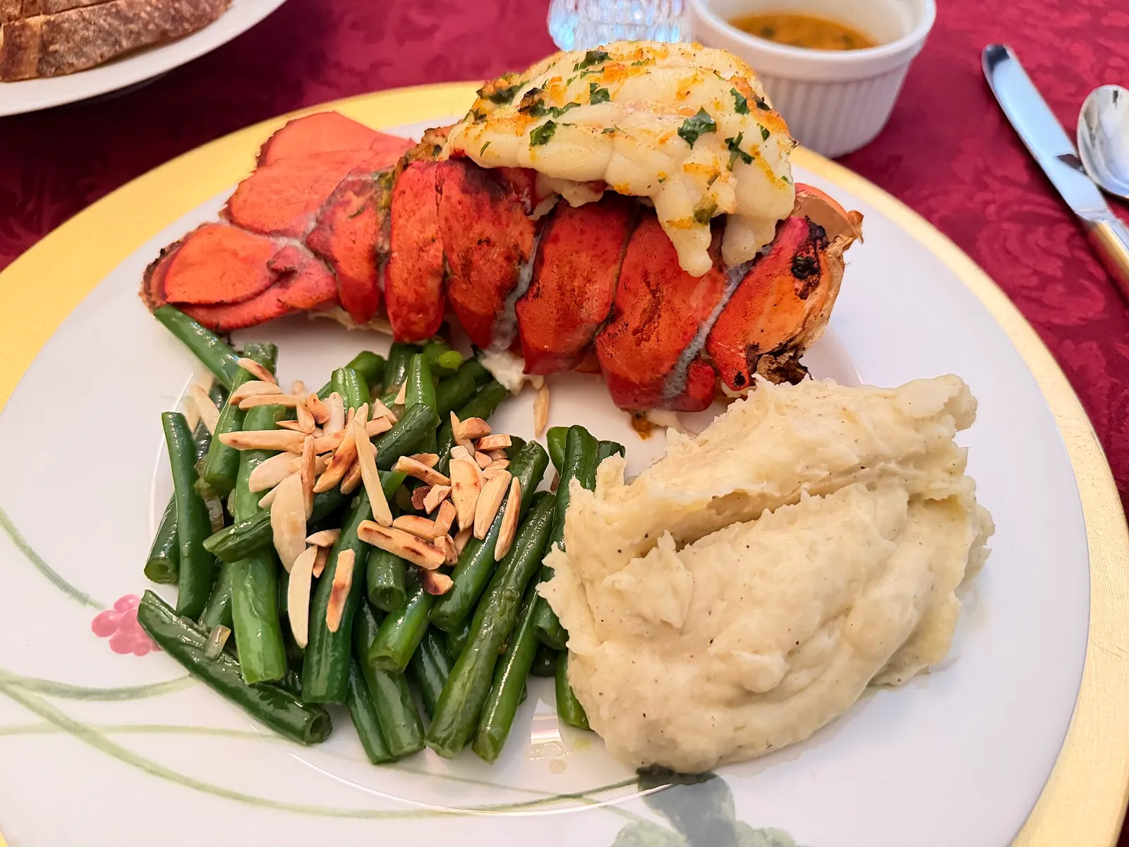 A grilled lobster tail served with green beans and mashed potato