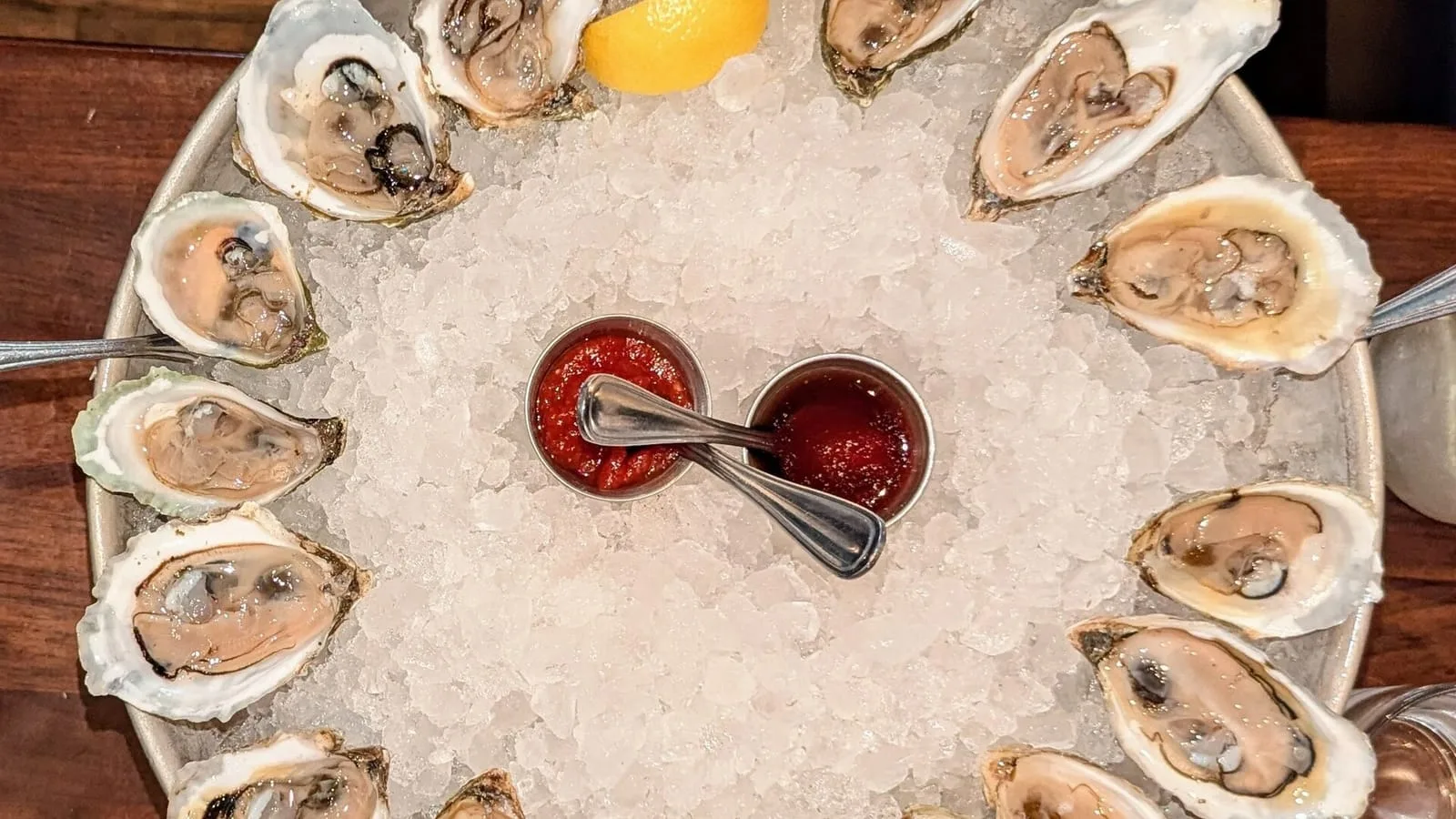 Un plateau d'huîtres ouvertes sur un lit de glace, avec citron et sauce mignonnette