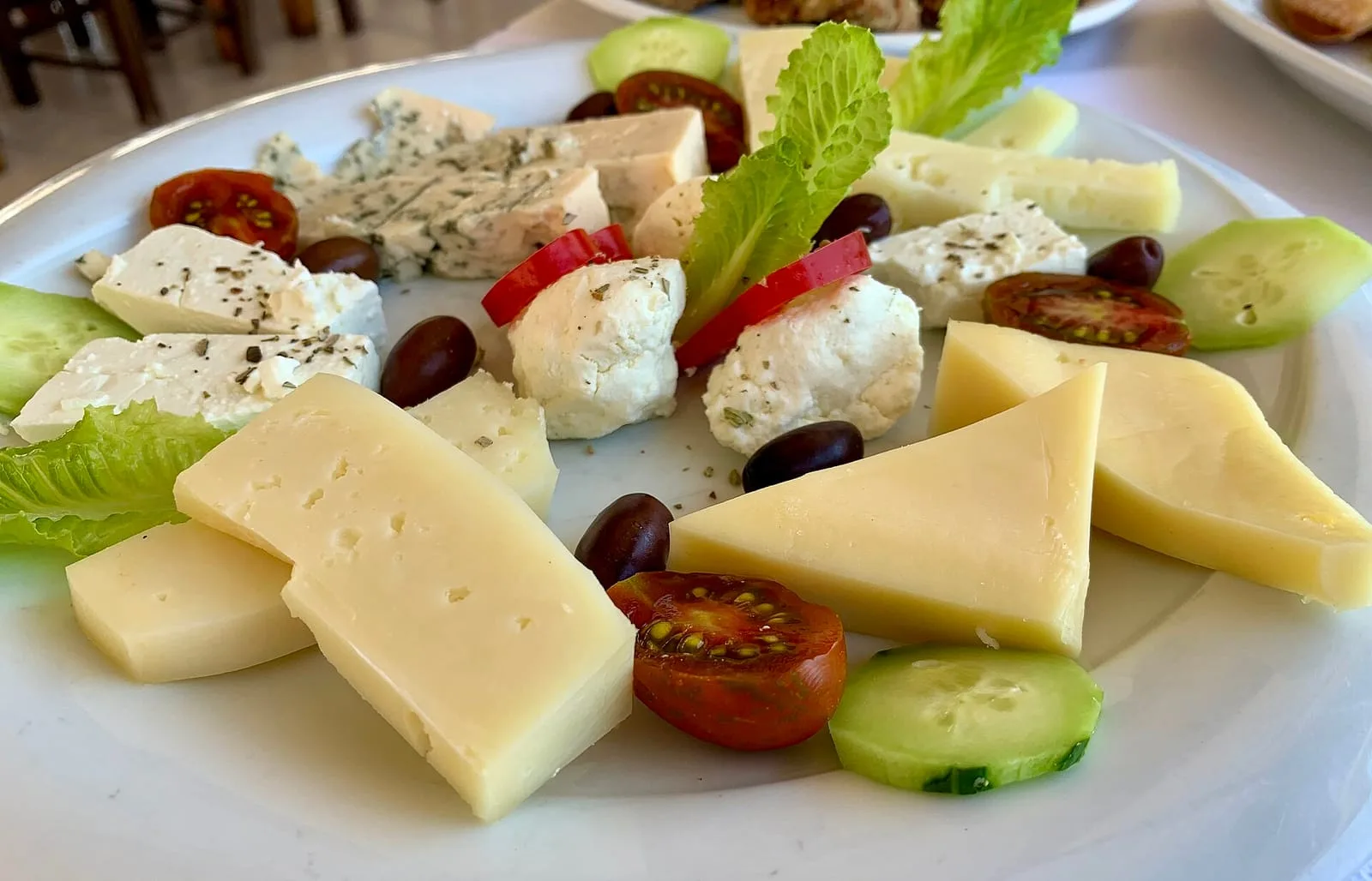 A cheese board with blue cheese, feta, hard cheeses, olives and cherry tomatoes