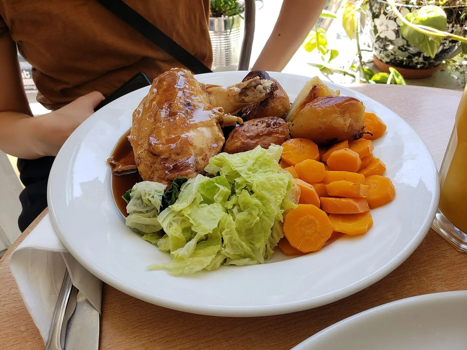 A plate of roast chicken with gravy, roast potatoes, carrots and cabbage