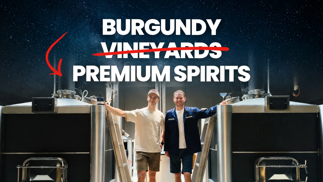 Maxime Girardin, in a blue Pegasus jacket, and Antoine standing between two tall stainless-steel stills at the Pegasus distillery in Meursault